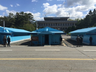 South Korean and American soldiers stood in very precise locations near the row of blue buildings (meeting rooms for North and South leaders). North Korean soldiers watched from the far building.